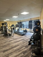 Uma academia com diversos equipamentos de exercício, incluindo esteiras, elípticos e estações de musculação.