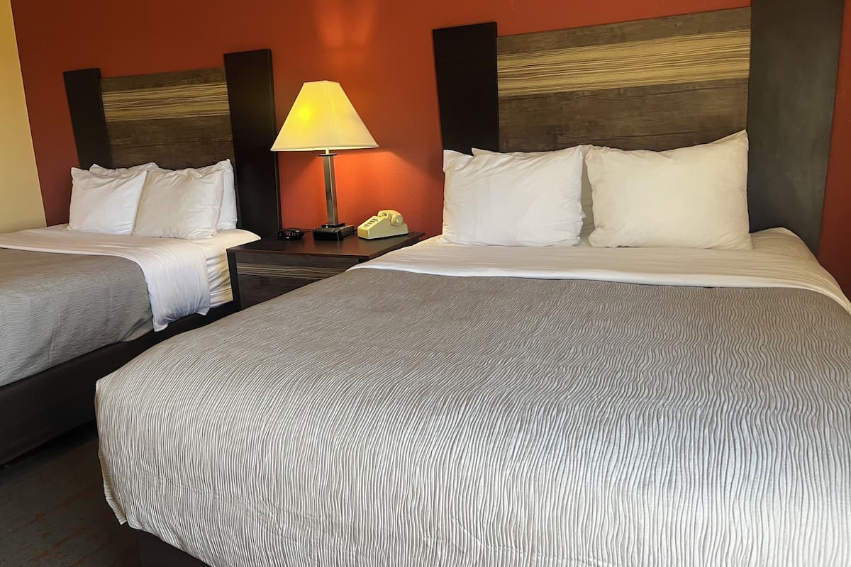 Une chambre d’hôtel avec deux lits, une table de chevet avec une lampe et un téléphone.