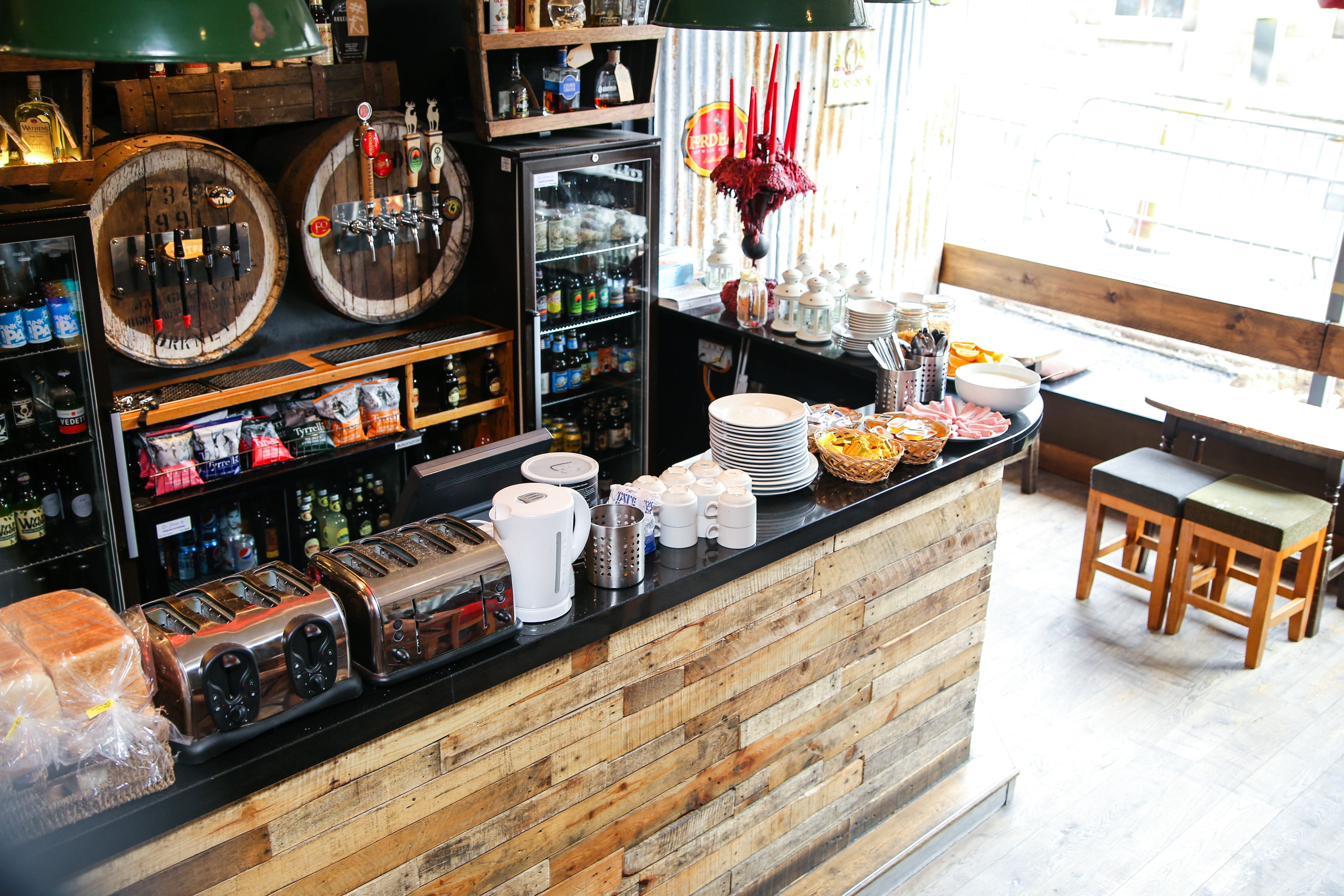 A bar area with wooden accents, a refrigerator, and various bottles.