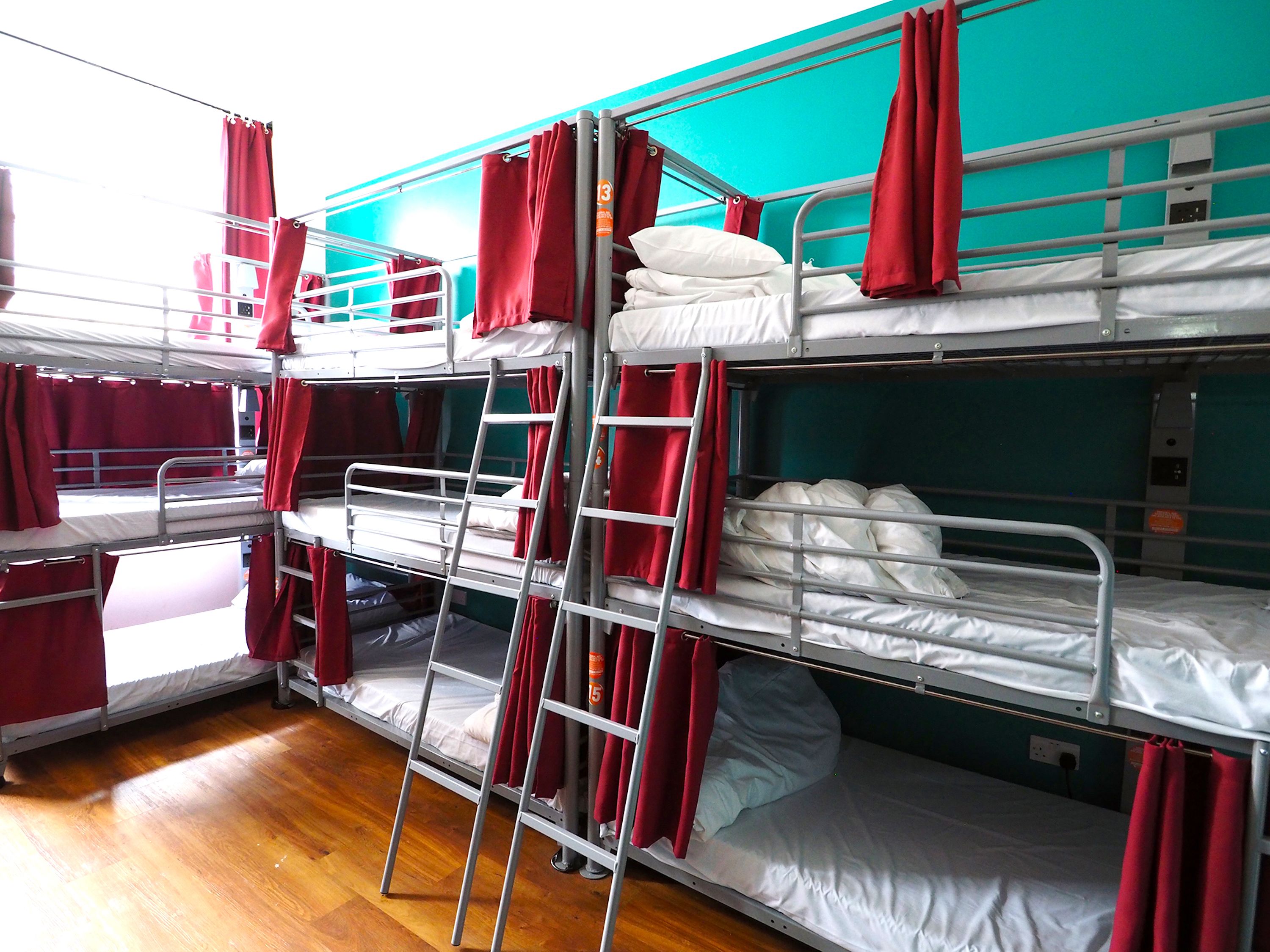 Camera con letto a castello, ringhiere in metallo e tende rosse.