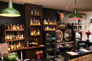 A bar with shelves of liquor bottles, a refrigerated display, and a cow skull decoration.