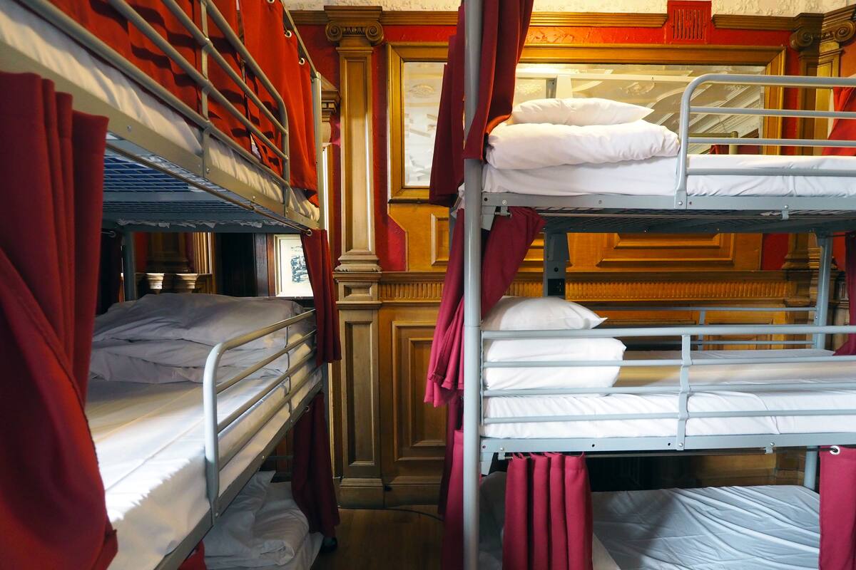 A room with bunk beds, red curtains, and wooden paneling.