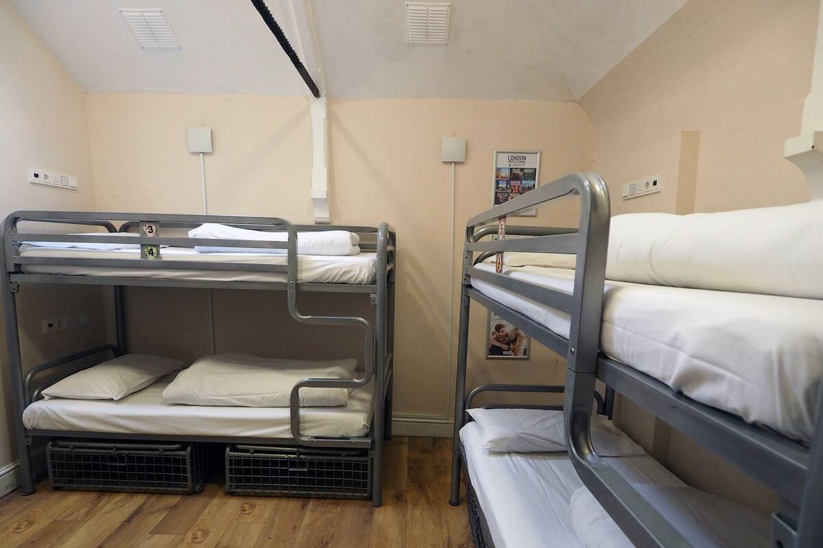 A bunk room with two bunk beds, wooden flooring, and a poster on the wall.