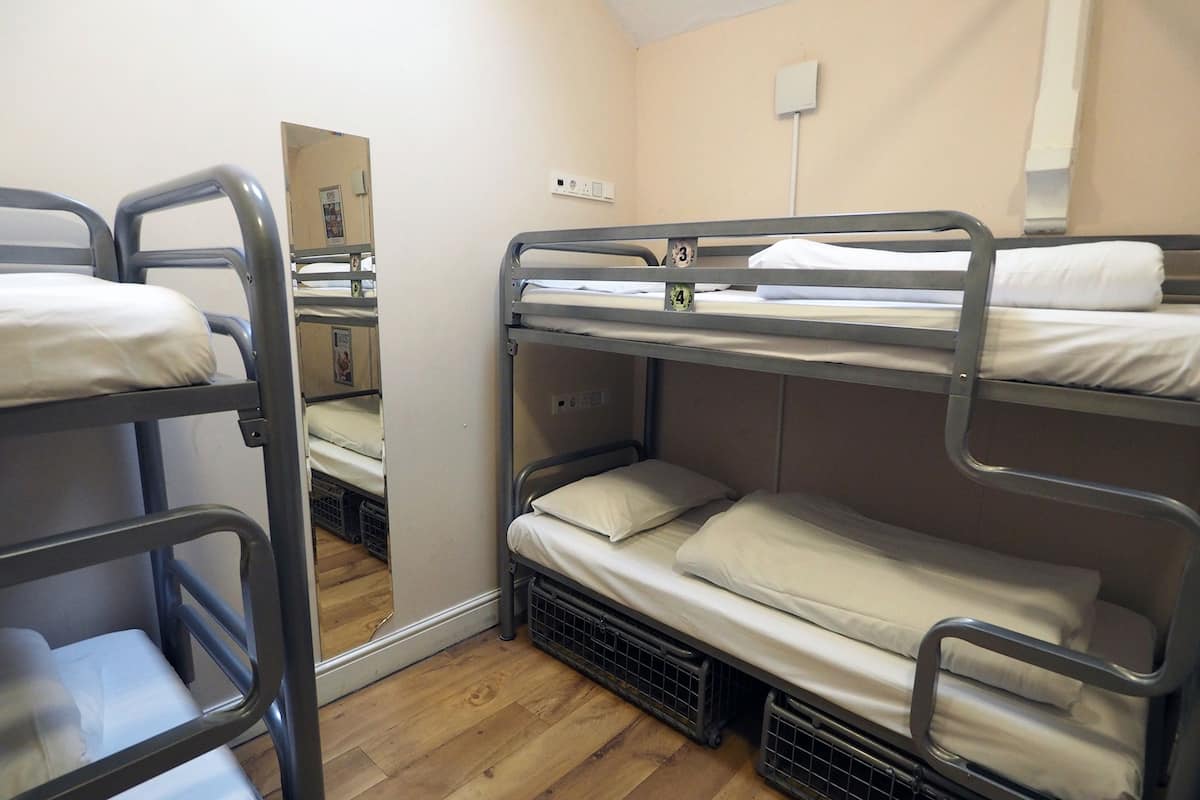 A bunk bed room with wooden flooring and a mirror on the wall.