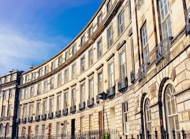A historic building with a curved facade, multiple windows, and ornate iron balcony railings.