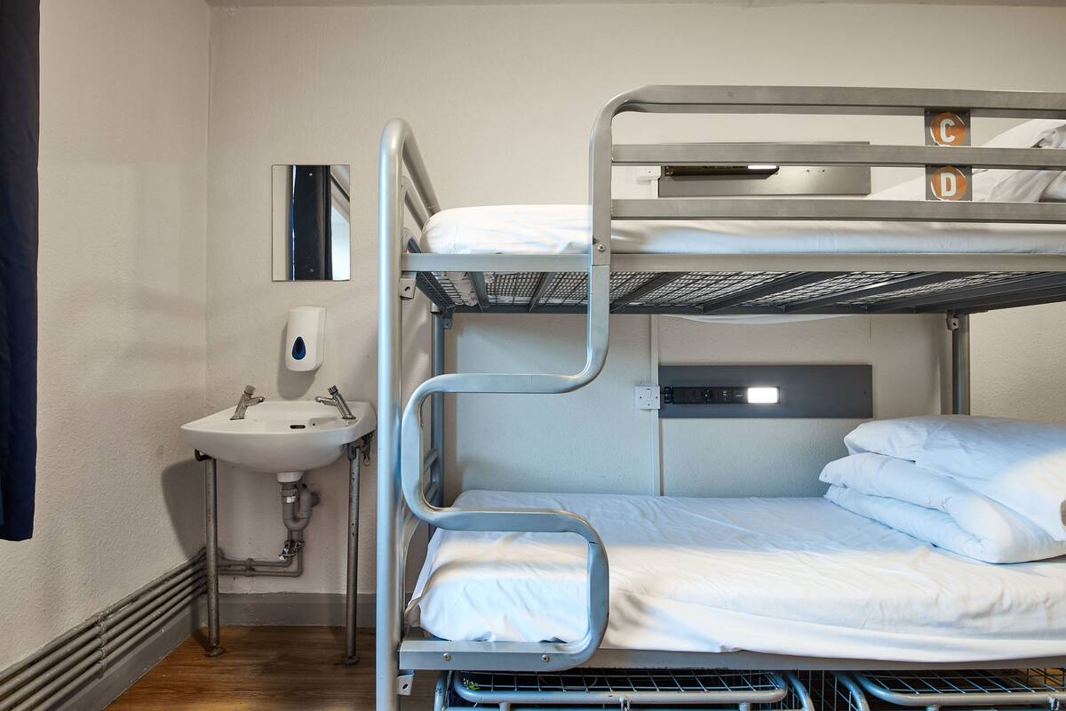 A bunk bed with a sink and a mirror in a hotel room.