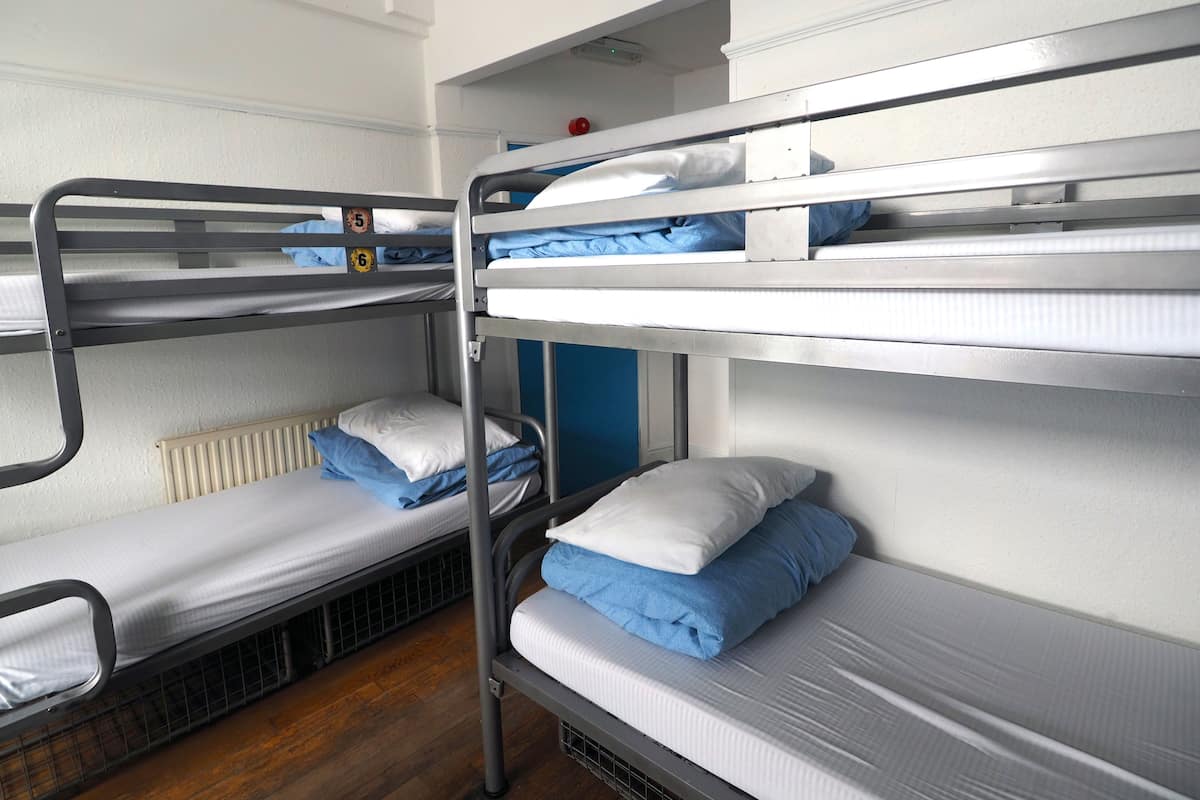 A bunk bed room with metal railings, white bedding, and a blue wall.