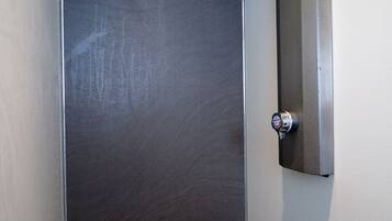 A closed door with a metallic handle and a small, rectangular object attached to the wall above it.
