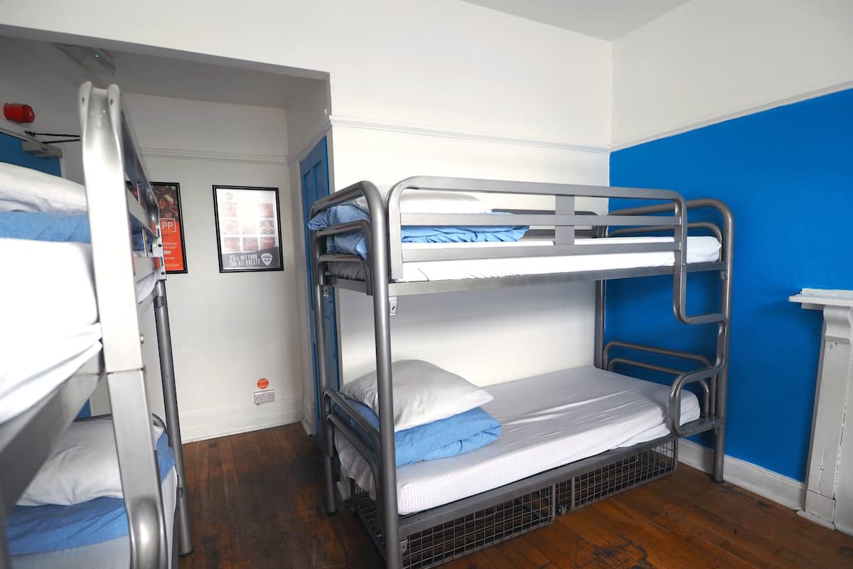 A bunk bed room with a blue wall and wooden flooring.