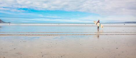 A beach with a person holding a surfboard.