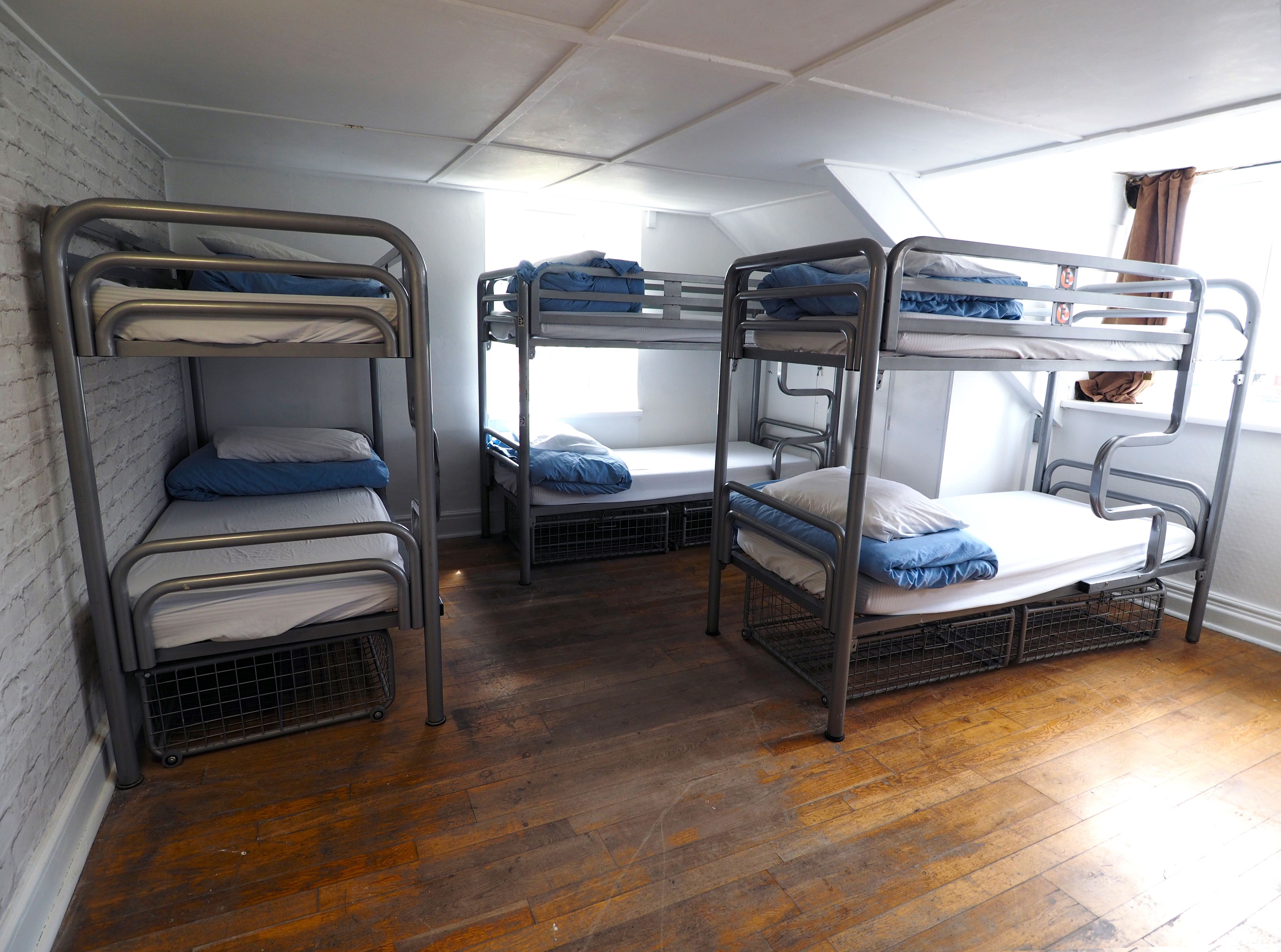 Une chambre de dortoir avec des lits superposés, un plancher en bois et un plafond en pente.