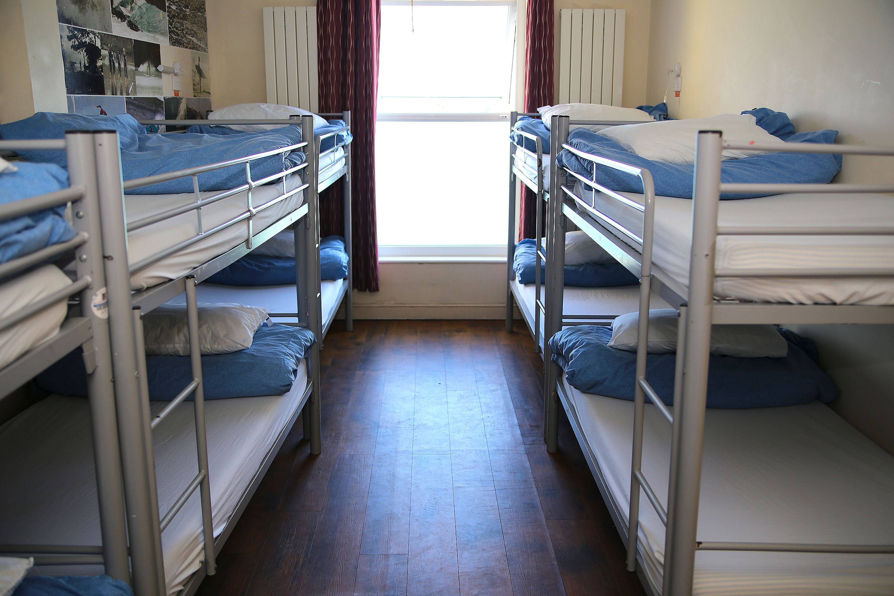 Un dormitorio con literas, suelo de madera y ventana con cortinas.