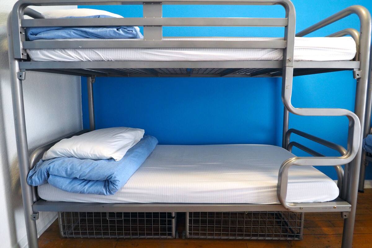 A bunk bed with two levels, each with a mattress and pillows.