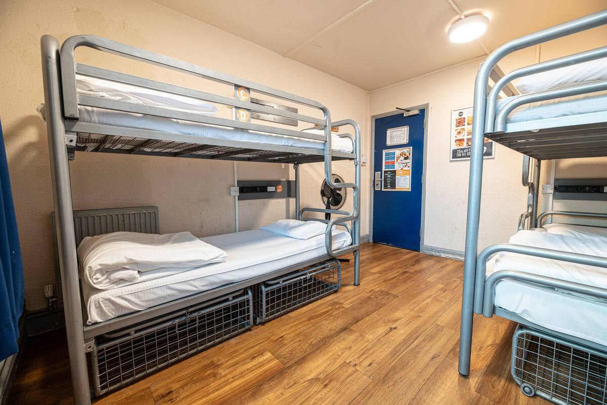 A bunk bed room with a blue door, a radiator, and a poster on the wall.