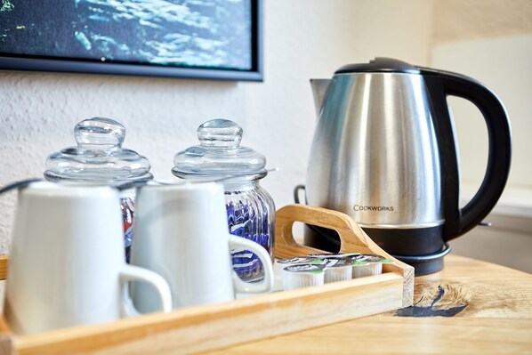 Una encimera de cocina con una cafetera, frascos y tazas.