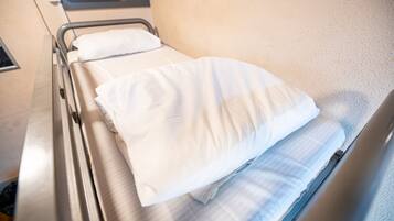A hospital bed with white linens and a headboard.