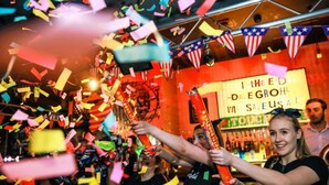 Celebración con confeti y serpentinas, un cartel que dice 'I THEED DAVE GROHL' a la vista, y una zona de bar al fondo.