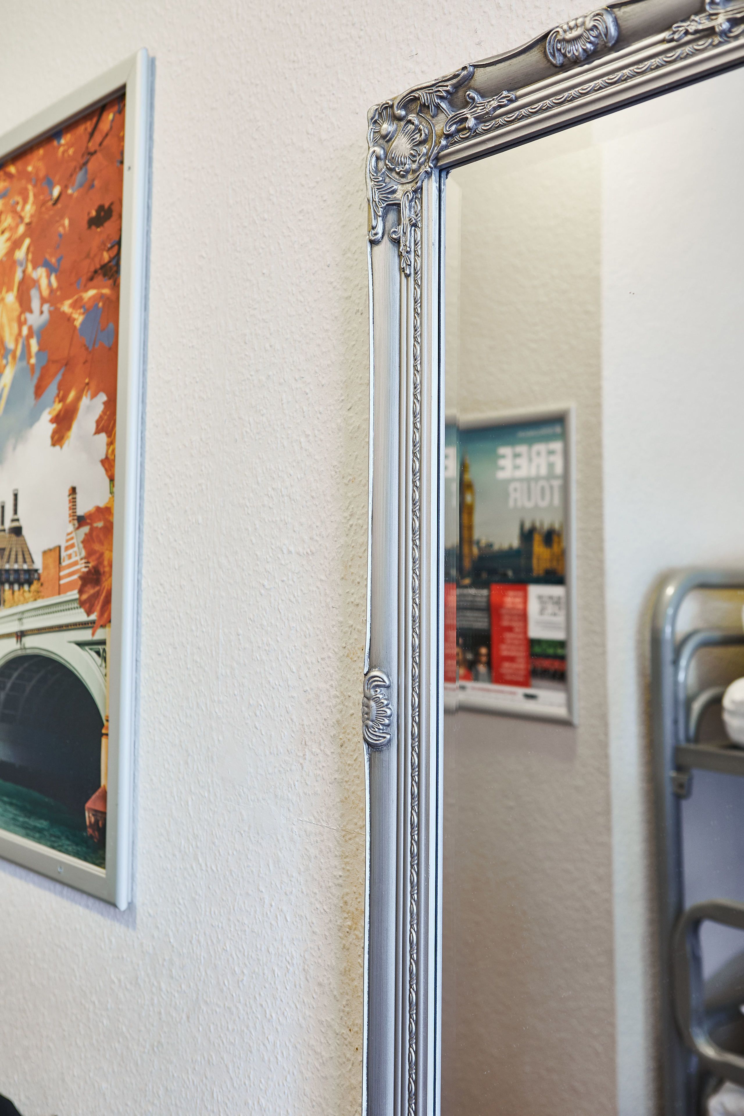 A bathroom with a large mirror, a towel rack, and a poster on the wall.