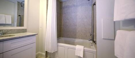 A bathroom with a bathtub, a shower, a sink, and a mirror.