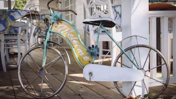A turquoise bicycle with a 'Welcome' sign on the front, parked on a wooden deck.