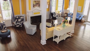 A living room with a fireplace, a blue sofa, a striped armchair, and a white console table with a vase of flowers. - Colonial Inn in Harbor Springs (Harbor Springs)