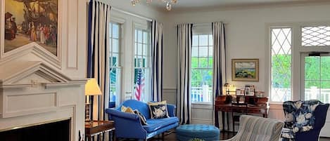 A spacious living room with a fireplace, a chandelier, and a blue sofa.