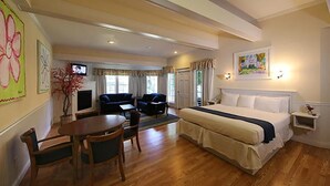 A hotel room with a bed, a TV, a dining table with chairs, and a sofa. - Colonial Inn in Harbor Springs (Harbor Springs)