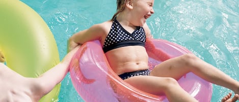 Una persona flota en un círculo inflable rosa en una piscina.