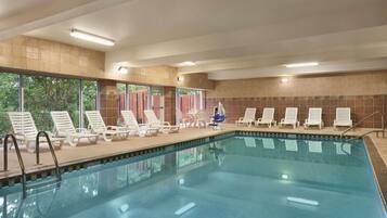A swimming pool with lounge chairs and a view of trees.