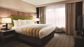 A hotel room with a large bed, two bedside tables with lamps, a flat-screen TV, and a large window with curtains. - Country Inn & Suites by Radisson, Newnan, GA (Newnan)