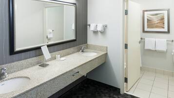 Un baño moderno con un espejo grande, dos lavamanos y una zona de ducha.