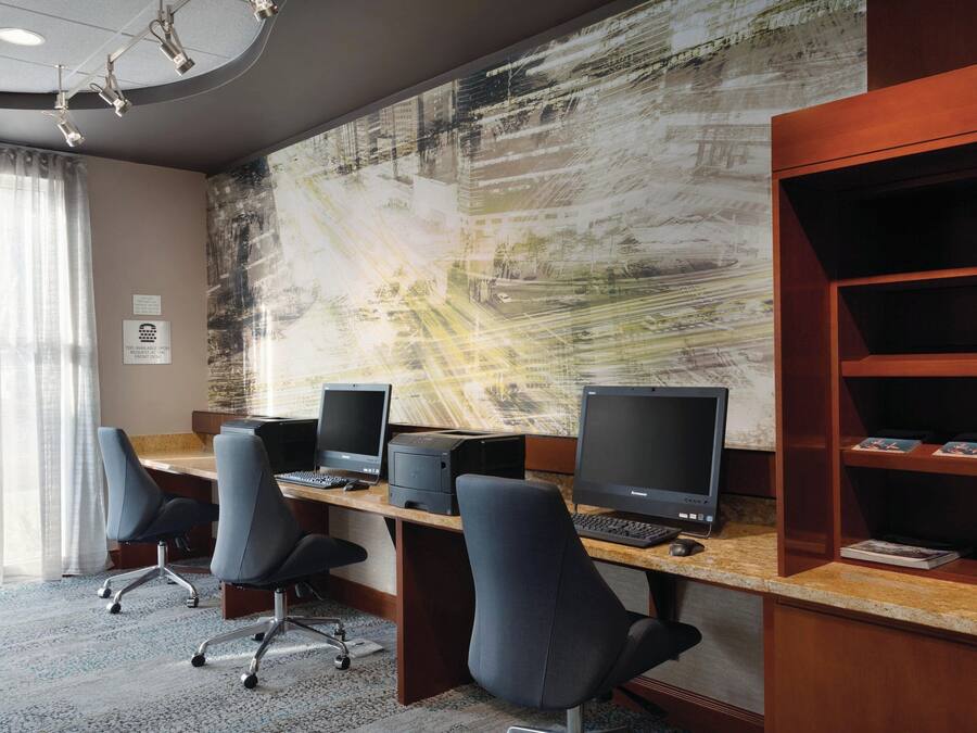 A modern office space with a long desk, multiple computer monitors, and office chairs.