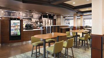 A modern restaurant with a bar area, seating arrangements, and a beverage refrigerator.