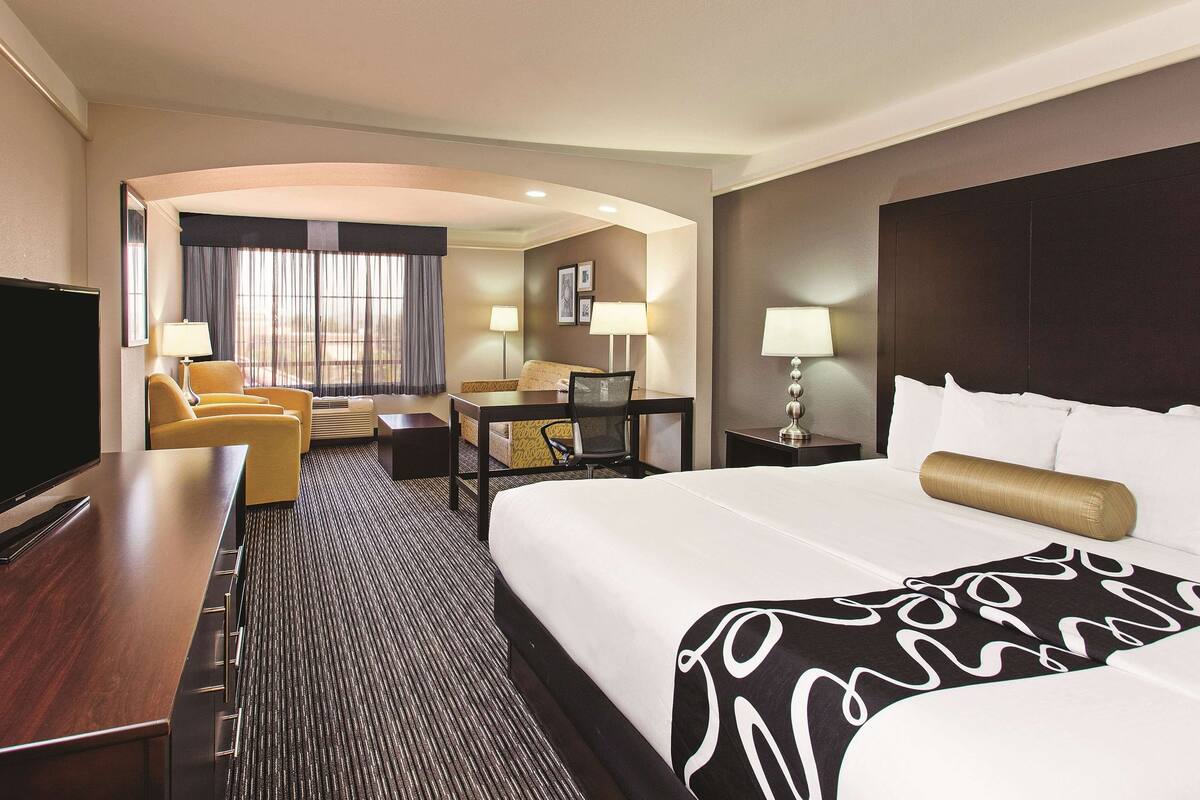 Ein Hotelzimmer mit einem großen Bett, einem Schreibtisch, einem Sessel, einem Fernseher und einer Couch.