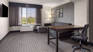 Ein Hotelzimmer mit Bett, Schreibtisch, Stuhl, Lampe und Fernseher.