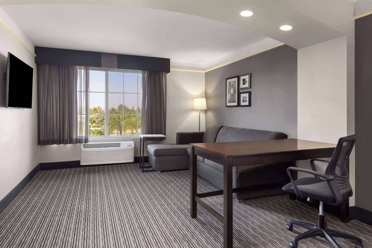 Ein Hotelzimmer mit Bett, Schreibtisch, Stuhl, Lampe und Fernseher.
