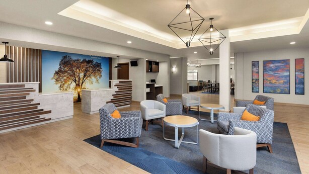 Eine geräumige Lobby mit moderner Möblierung, einer Treppe und einer großflächigen Baum-Mural.
