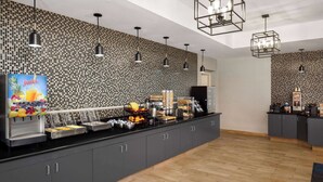 Eine moderne Küche mit schwarzem und weißem Mosaik-Spritzschutz, Edelstahlgeräten und einem Saftspender.