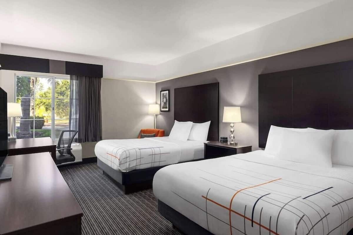 Ein Hotelzimmer mit zwei Betten, einem Schreibtisch und einem Sessel.