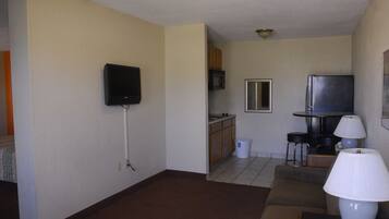 A living room with a television, a kitchen area, and a dining table with chairs.