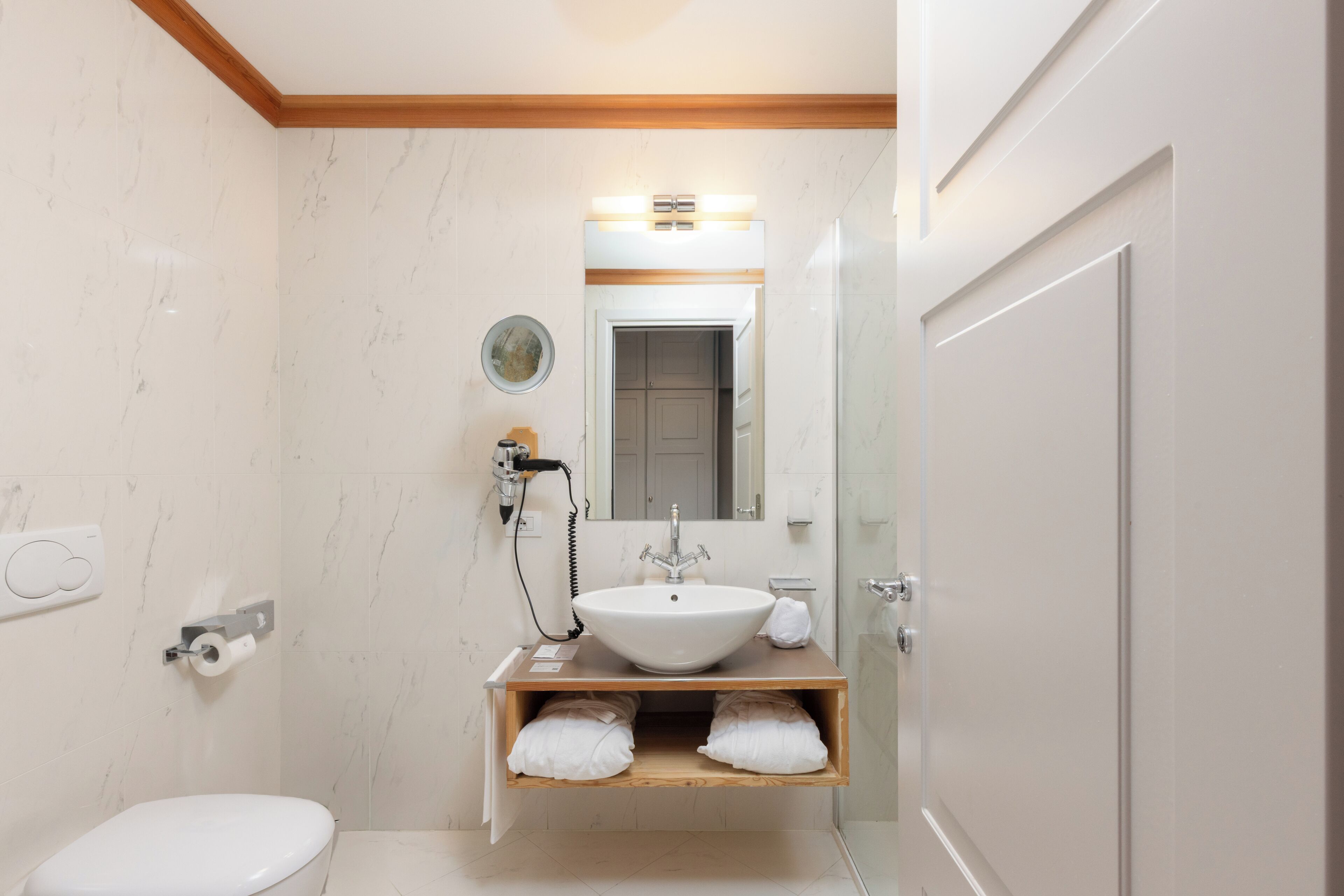 A bathroom with a white sink, mirror, and toilet.