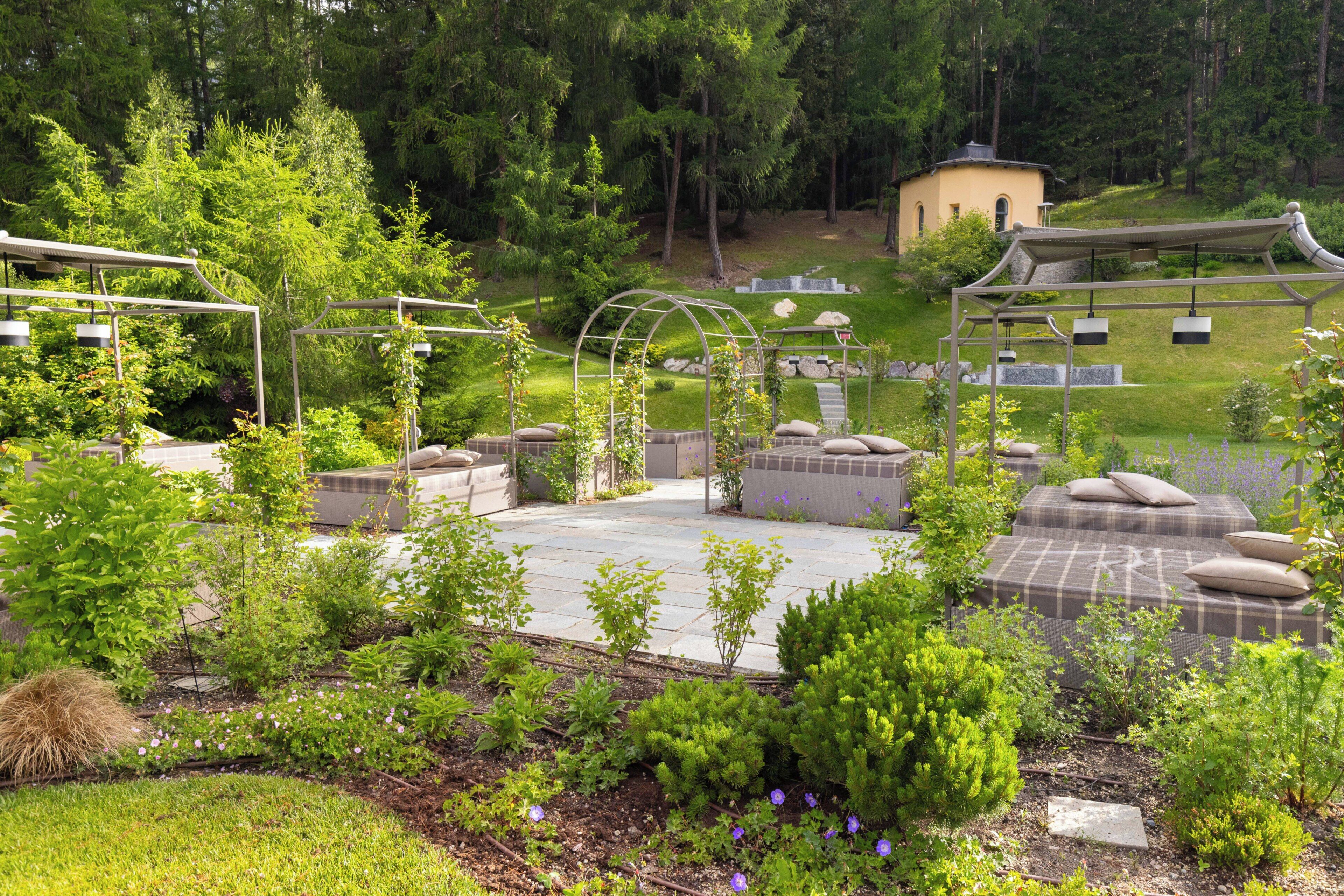 Ein Garten mit einem Pavillon, Sitzbereichen und einem kleinen Gebäude.