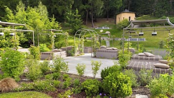 A garden with a gazebo, seating areas, and a small building.