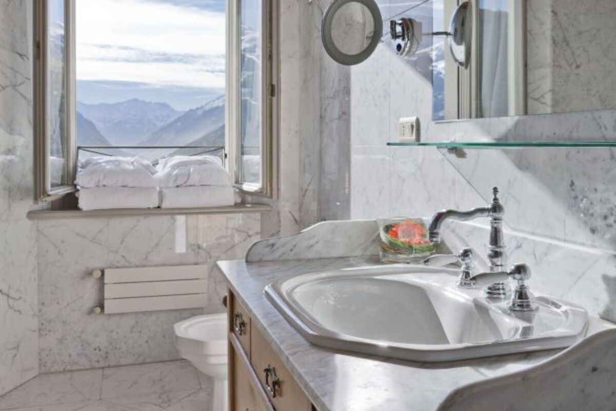 A bathroom with a large window, a sink, and a mirror.
