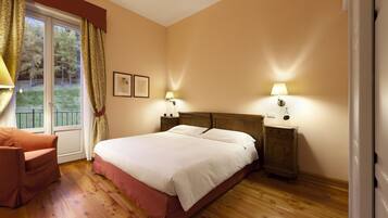 Une chambre à coucher avec un grand lit, deux tables de chevet avec des lampes, un plancher en bois et une fenêtre avec des rideaux.