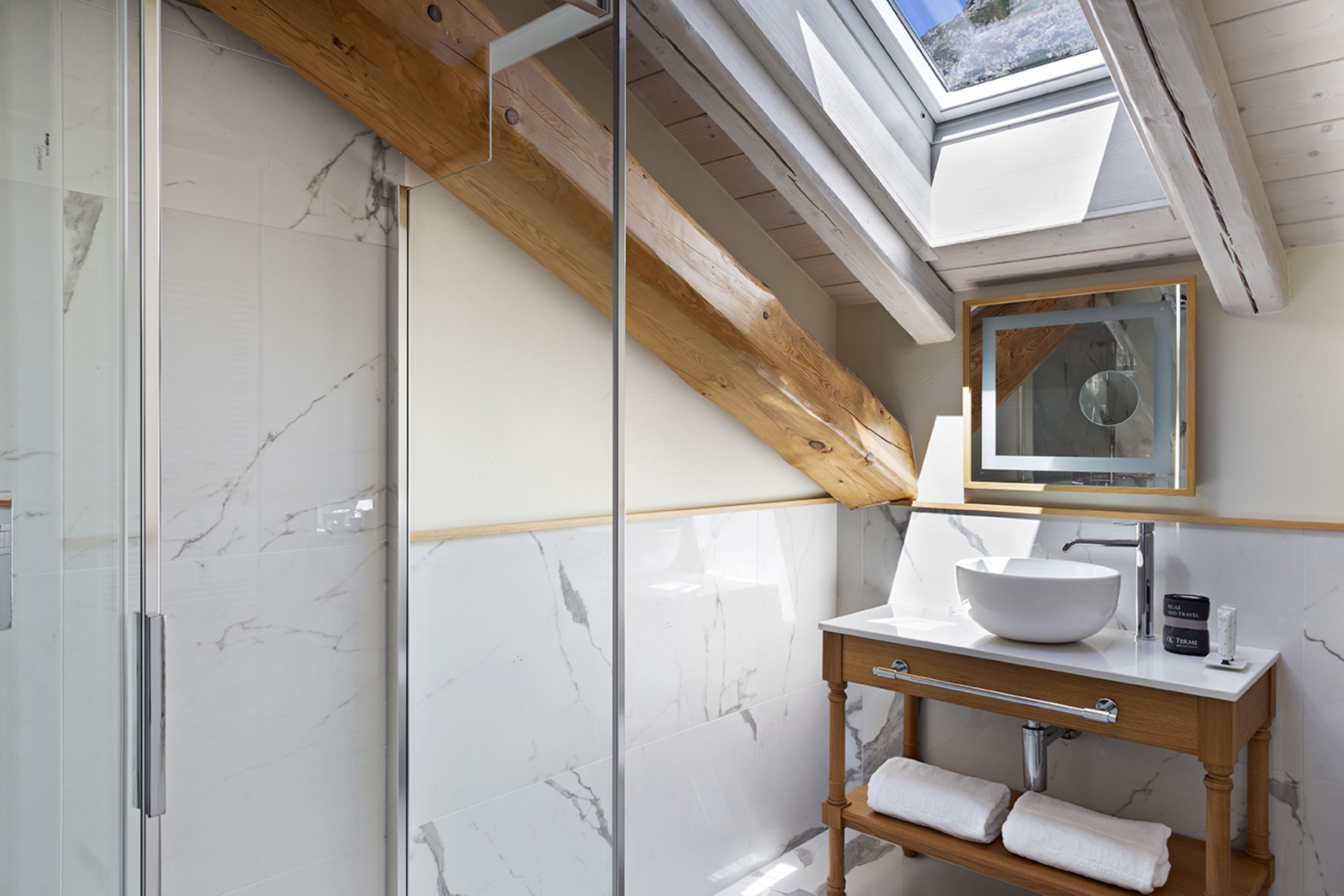 Een moderne badkamer met dakraam, een groot wit wastafelmeubel en een houten opbergkast.