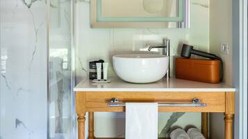 Un bagno con lavabo in marmo, mobile contenitore in legno e cabina doccia in vetro.