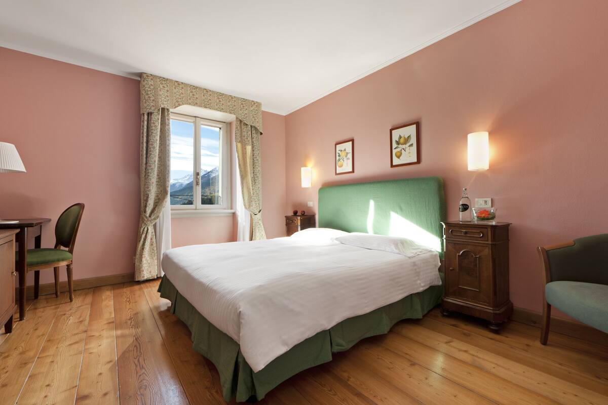 Ein Schlafzimmer mit Bett, Stuhl, Kommode und einem Fenster mit Vorhängen.