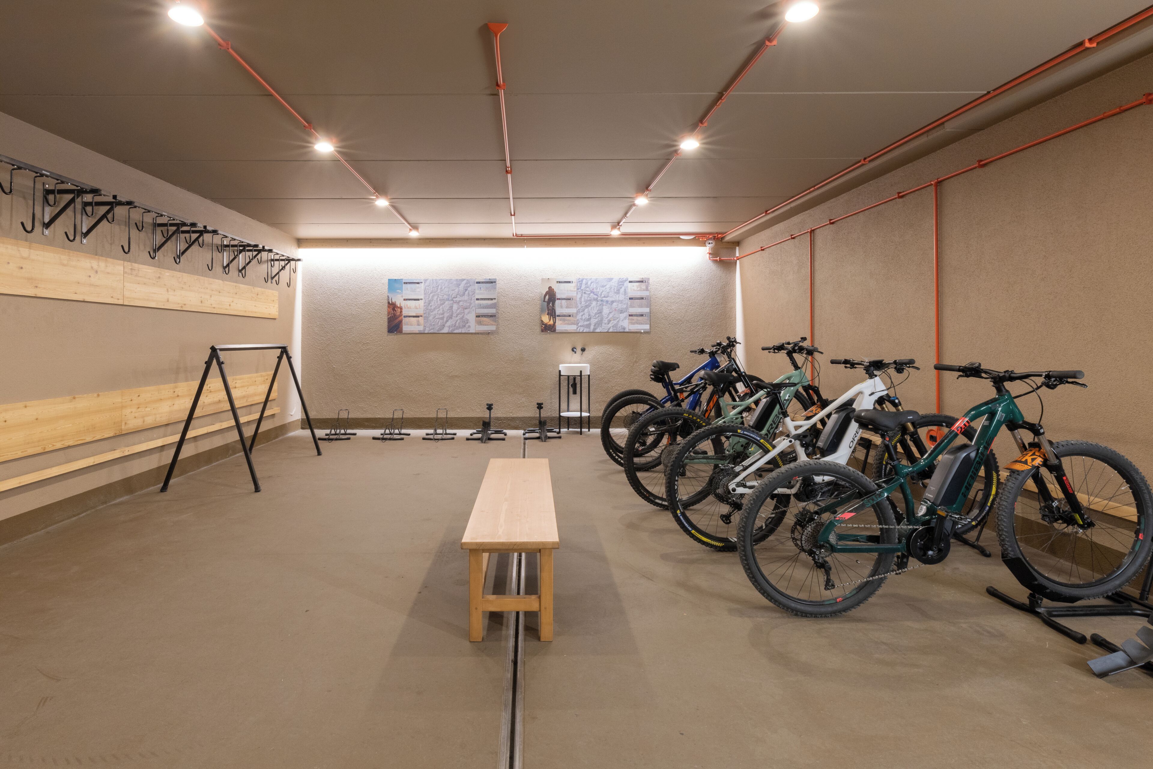 A room with a wooden bench, bicycles, and a wall-mounted bike rack.
