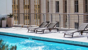 A rooftop pool with lounge chairs, a clear blue pool, and a building with large windows and decorative elements. - Apartments at Mandela Rhodes Place (Cape Town)